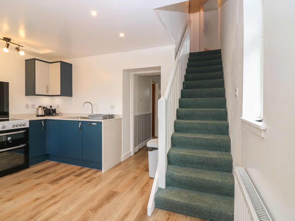 A kitchen with cabinets and a staircase at Alt na Voir in Tomintoul