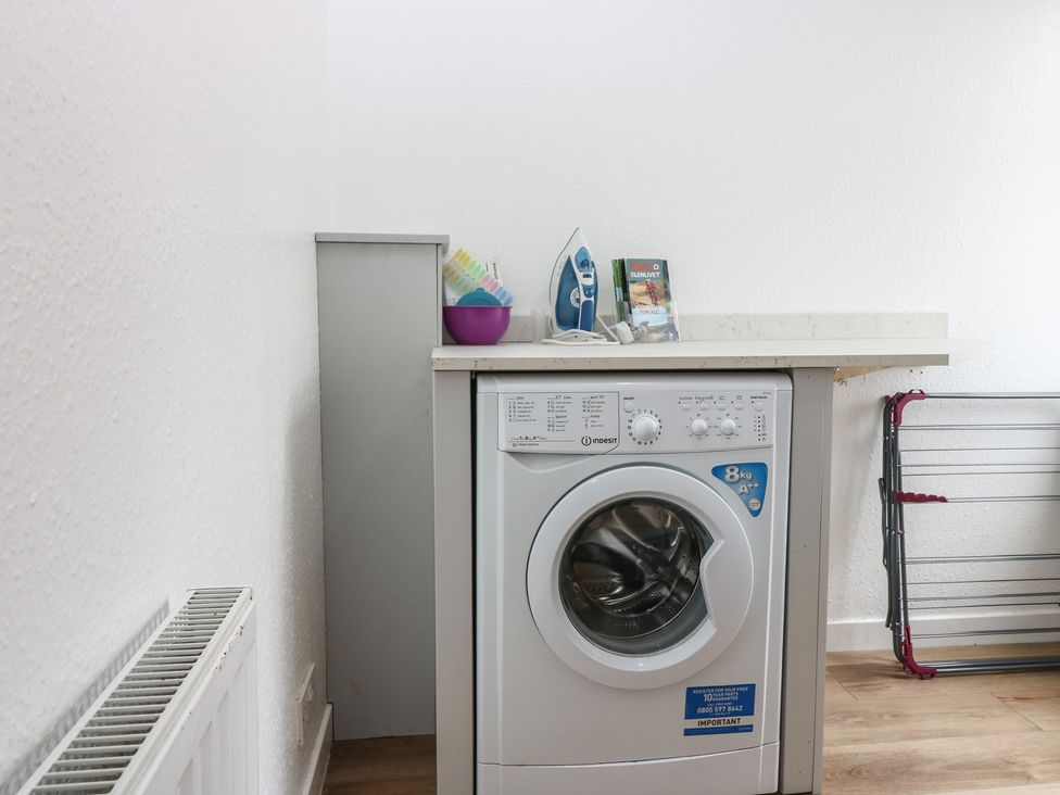 A laundry room with a washing machine and an iron at Alt na Voir Tomintoul