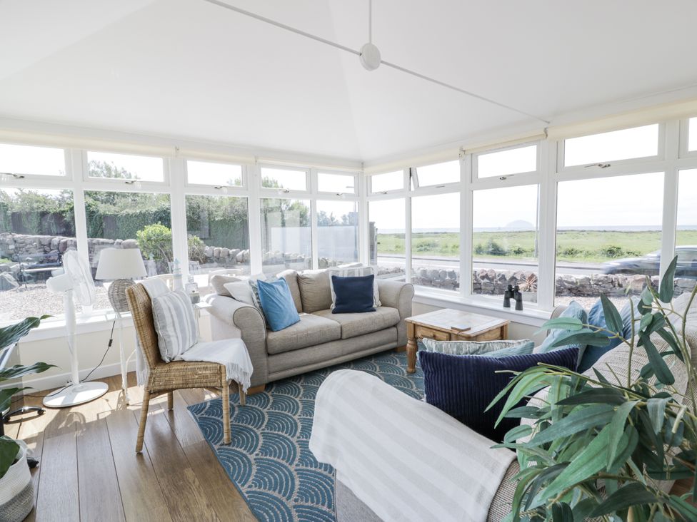 A conservatory with a sofa and coffee table at Ailsa Shores in Turnberry