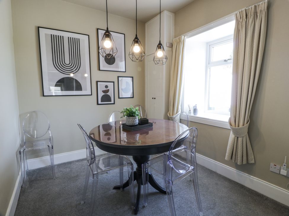 A dining room with a round table and transparent chairs at Ailsa Shores in Turnberry