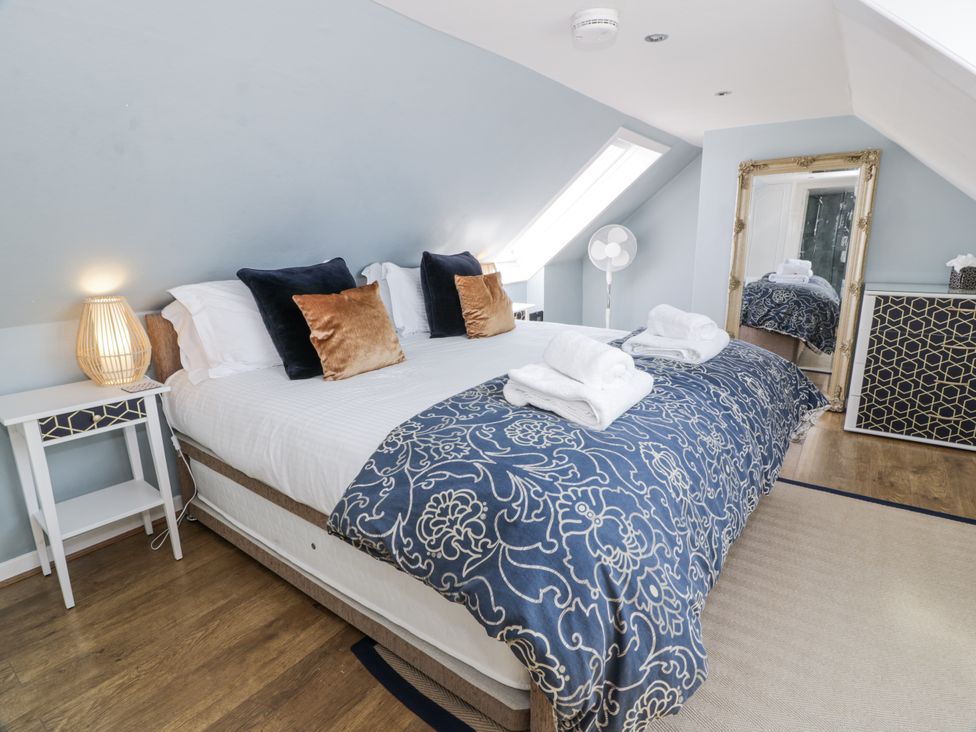 A bedroom with a bed, bedside table, and mirror at Ailsa Shores in Turnberry