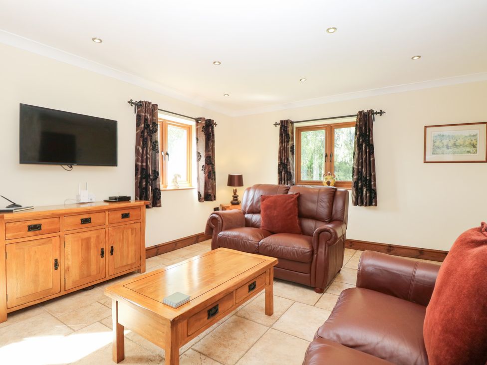 A living room with a tv and seating area at The Annexe in Litcham
