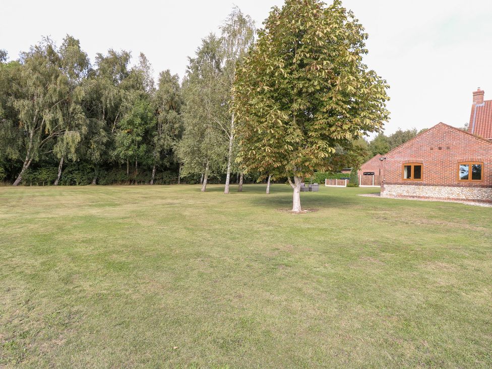 An outdoor area with trees and a brick house at The Annexe in Litcham