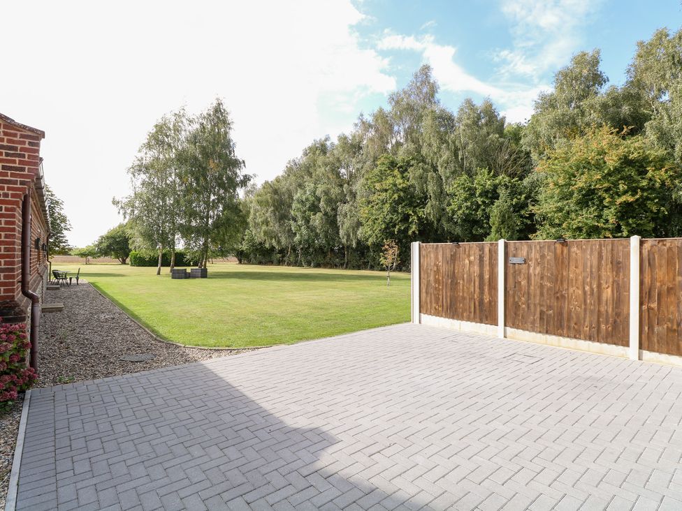 An outdoor space with a paved area and trees at The Annexe in Litcham