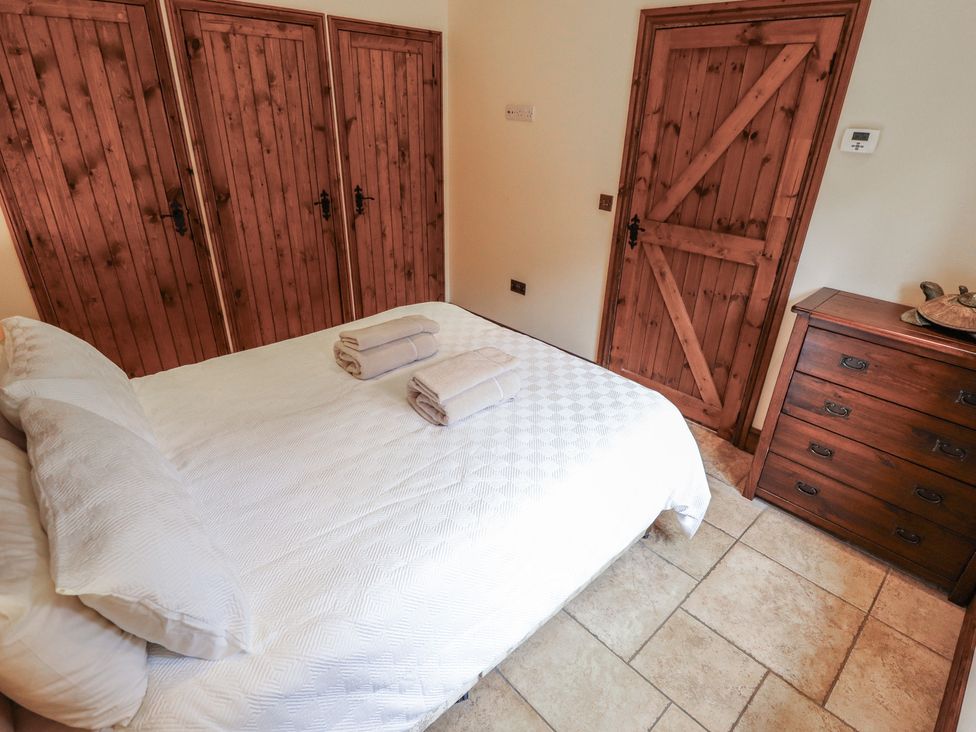 A bedroom with a bed and wardrobe doors at The Annexe in Litcham