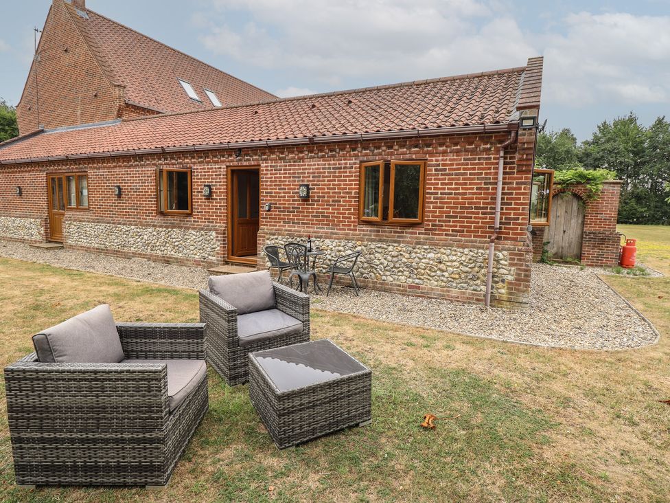 An outdoor area with a brick building and seating at The Annexe in Litcham