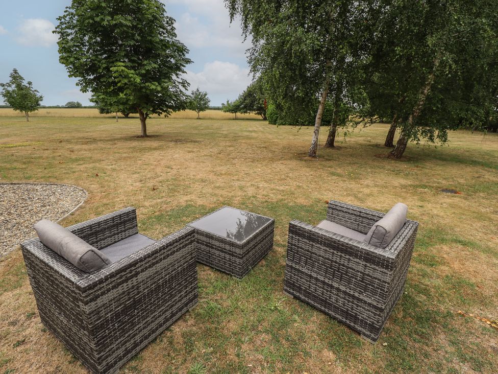 A seating area with rattan chairs and a table at The Annexe in Litcham