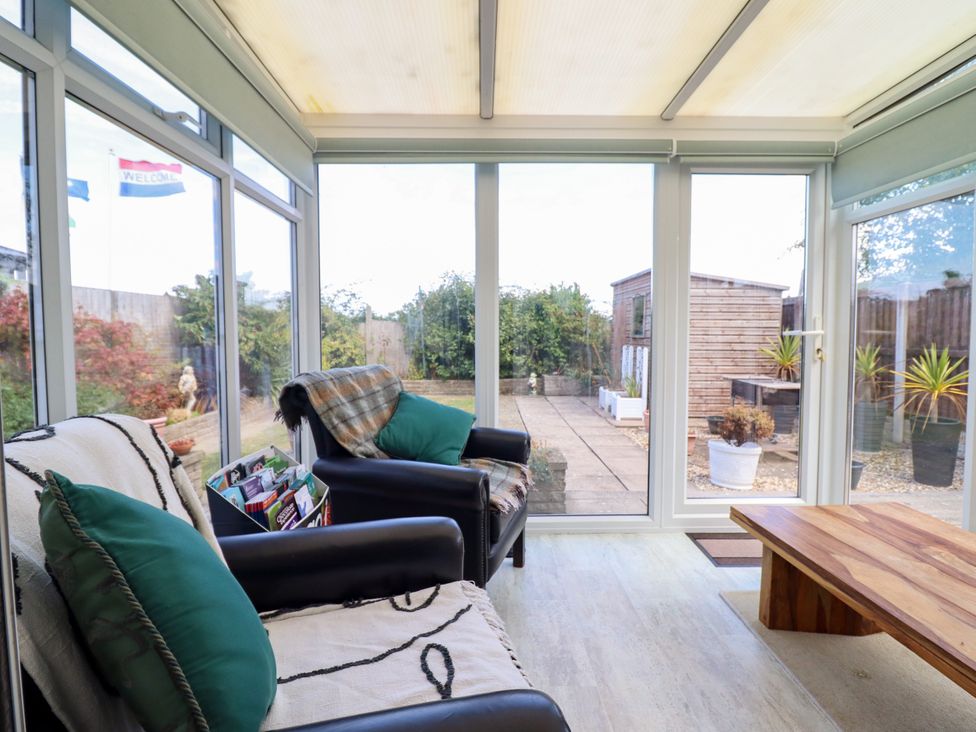 A conservatory with armchairs and a coffee table at Chy Bean Abergele