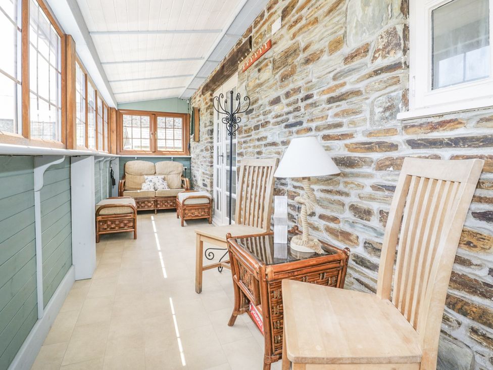 A conservatory with seating and tables at Dovecote in Gorran Haven