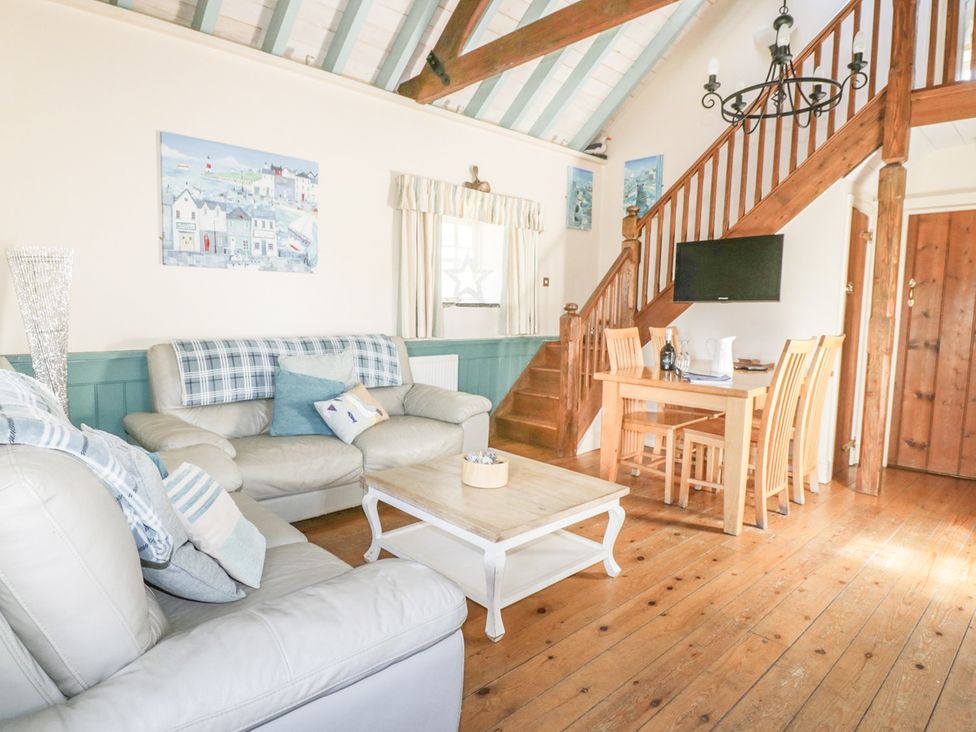 A living room with a sofa coffee table and dining area at Dovecote in Gorran Haven