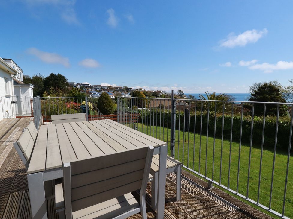 An outdoor area with a table and chairs overlooking the ocean at Treverrion in Gorran Haven
