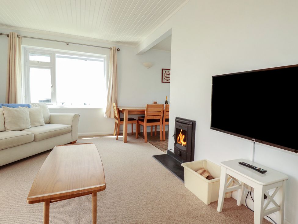 A living room with a sofa and dining area at Treverrion in Gorran Haven