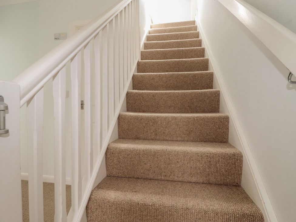 A staircase with carpet and a handrail at Treverrion in Gorran Haven