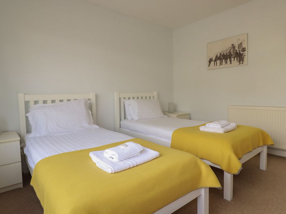 A bedroom with two beds and a painting at Treverrion in Gorran Haven