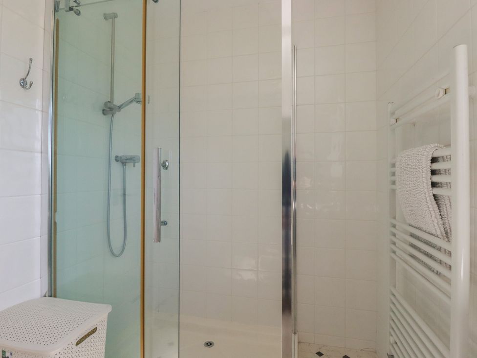 A shower with glass door and towel rack at Treverrion in Gorran Haven