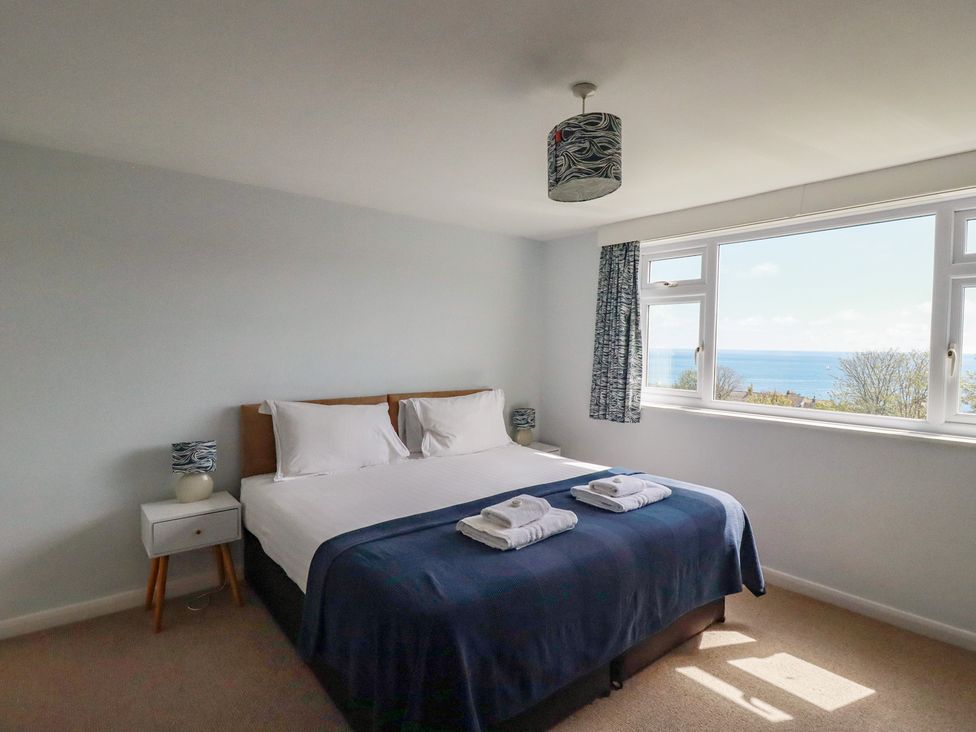 A bedroom with a bed and view of the sea at Treverrion in Gorran Haven