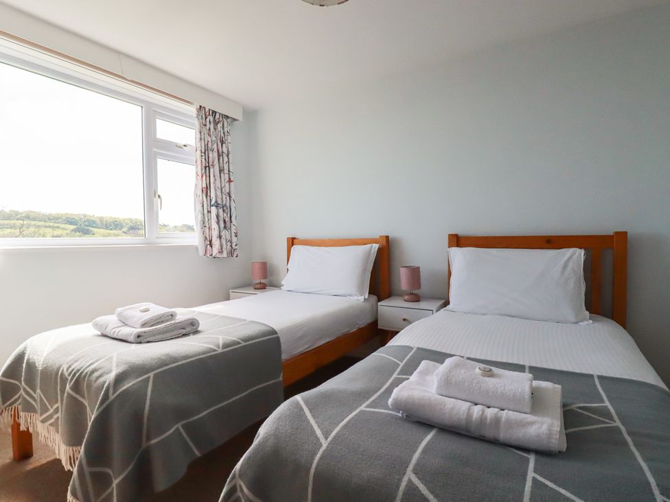 A bedroom with two single beds and a window at Treverrion in Gorran Haven