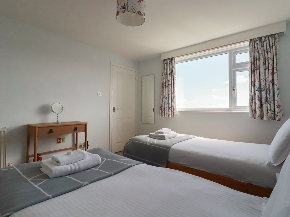 A bedroom with two beds and a table at Treverrion in Gorran Haven