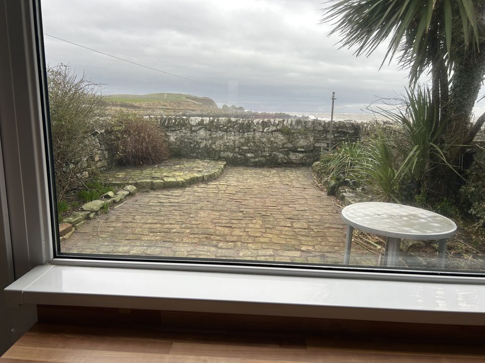 A garden view featuring a stone wall and a table at The Pink House Isle Of Whithorn