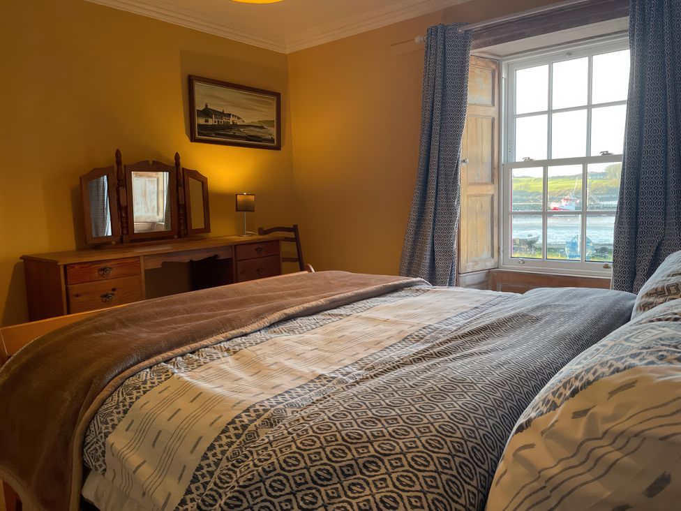 A bedroom with a bed and dresser at The Pink House in Isle Of Whithorn