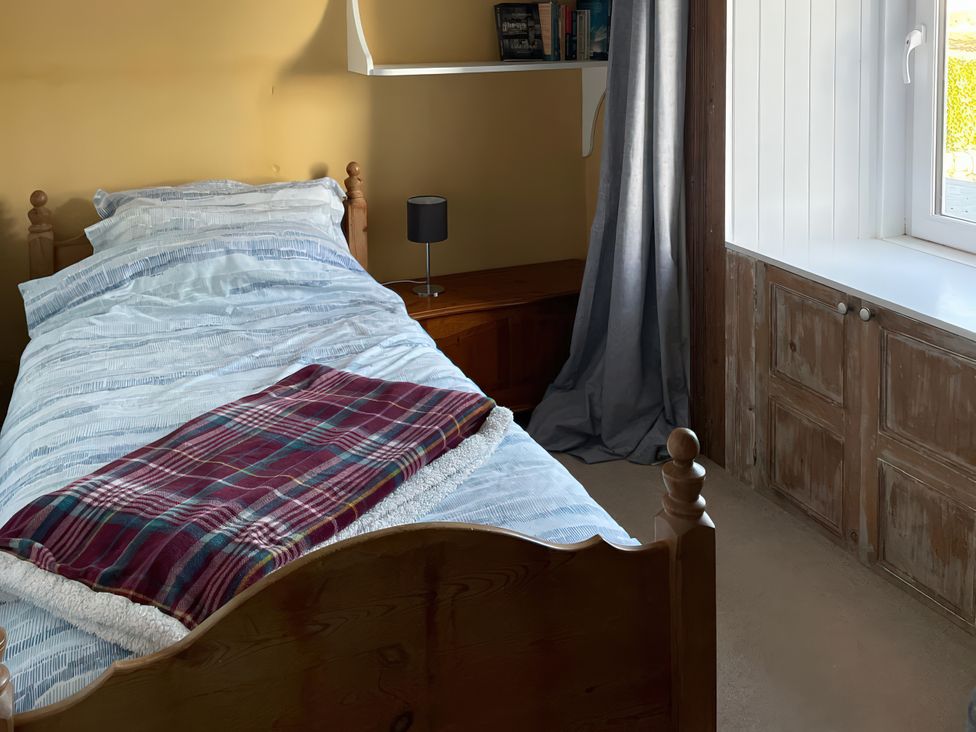 A bedroom with a bed and window at The Pink House Isle Of Whithorn