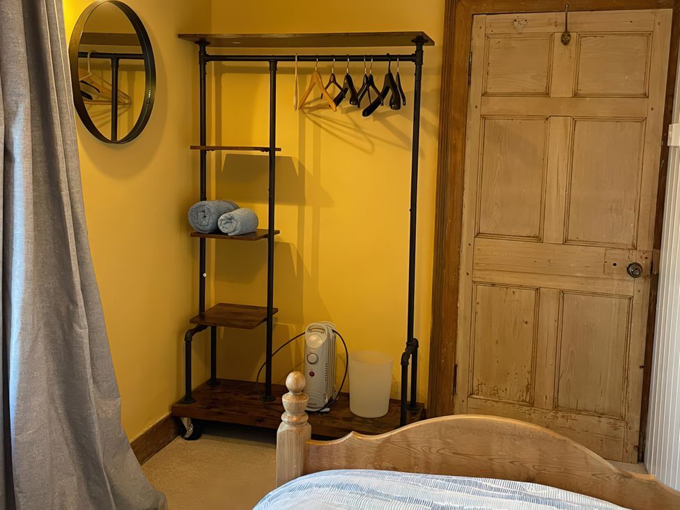 A bedroom with a clothing rack and towels at The Pink House in Isle Of Whithorn
