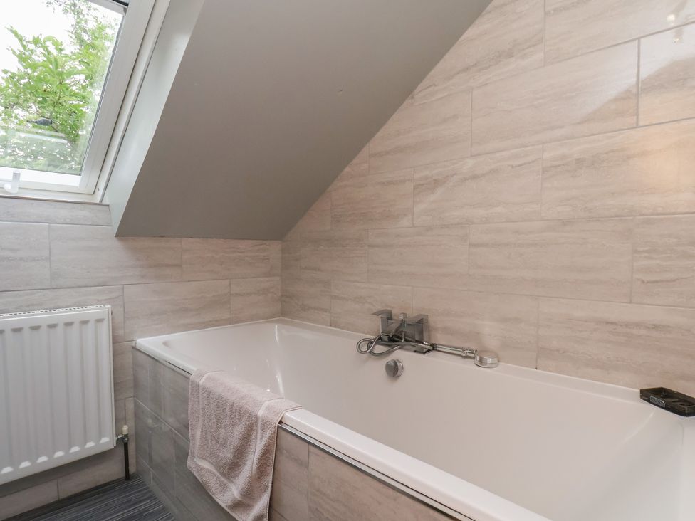 A bathroom with a bathtub and window at Fortunatus in Whitby