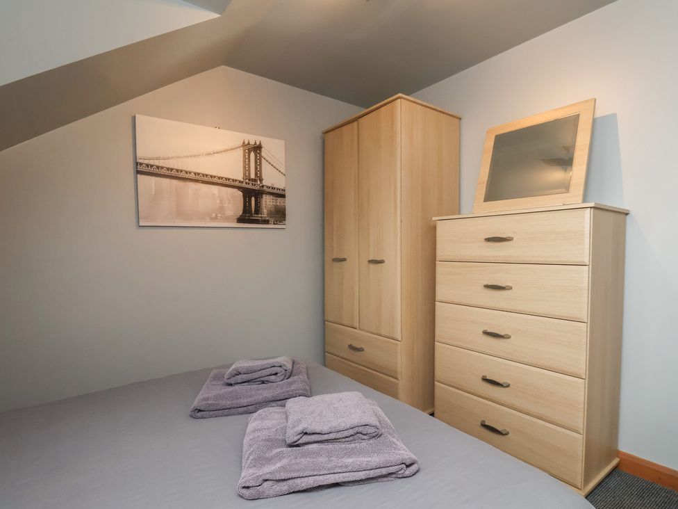 A bedroom with a bed, towels, wardrobe, and a chest of drawers at Fortunatus in Whitby