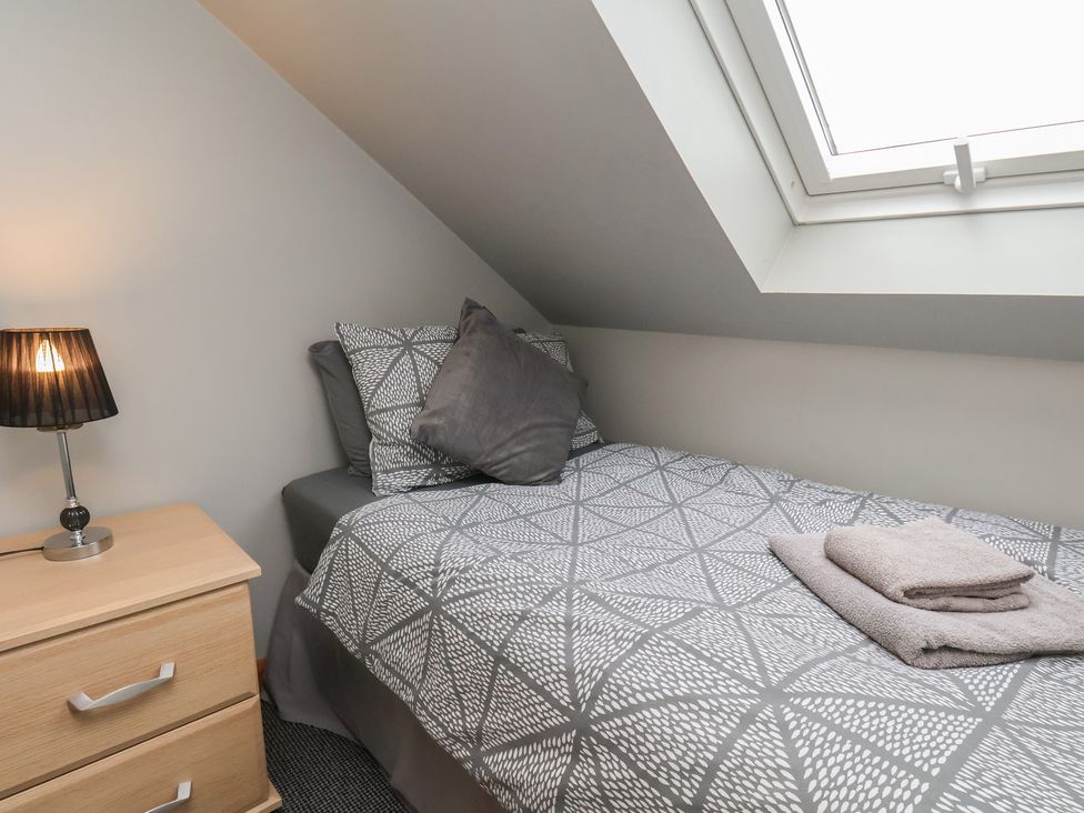 A bedroom with a single bed and bedside lamp at Fortunatus in Whitby
