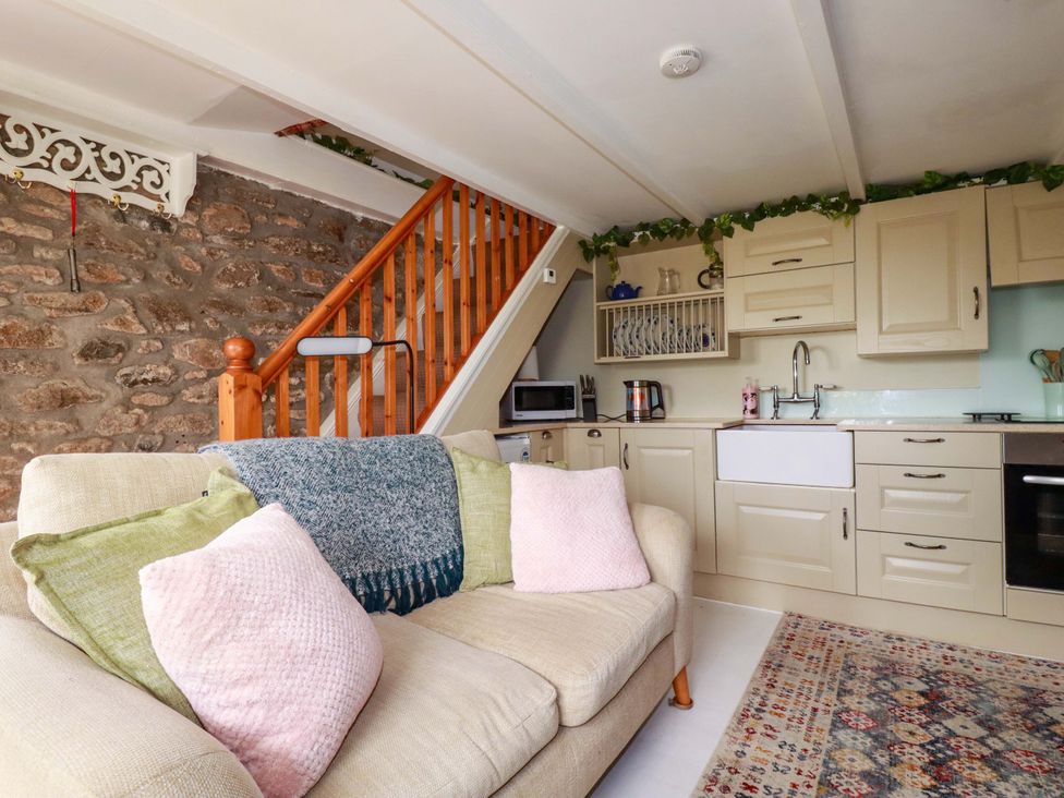 A living room with a sofa and kitchen area at Longview Cottage in Penwithick neat St Austell