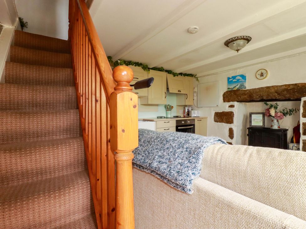 A living room with a staircase and kitchen cabinets at Longview Cottage Penwithick neat St Austell