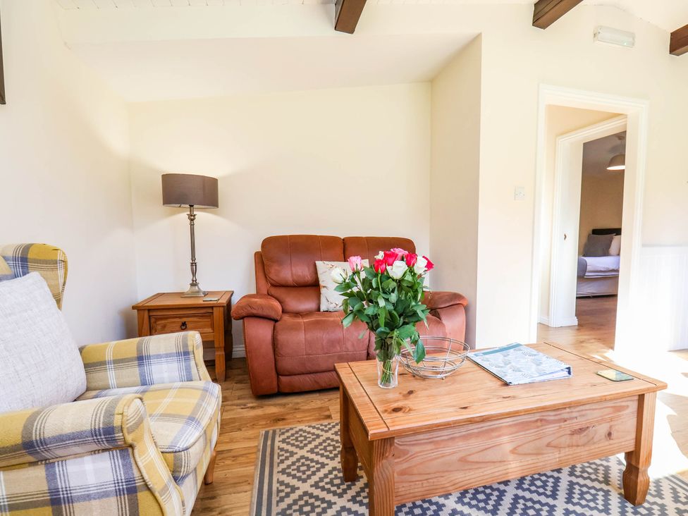 A living room with a sofa, table, and lamp at Snowdrop in Saltburn-by-the-Sea