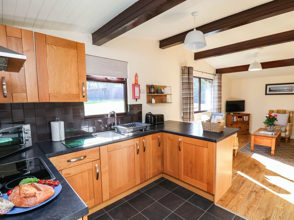 A kitchen with wooden cabinets and a sink at Snowdrop in Saltburn-by-the-Sea