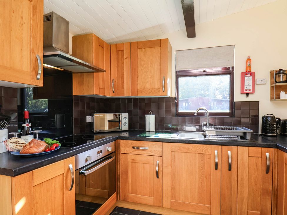 A kitchen with wooden cabinets and appliances at Snowdrop in Saltburn-by-the-Sea