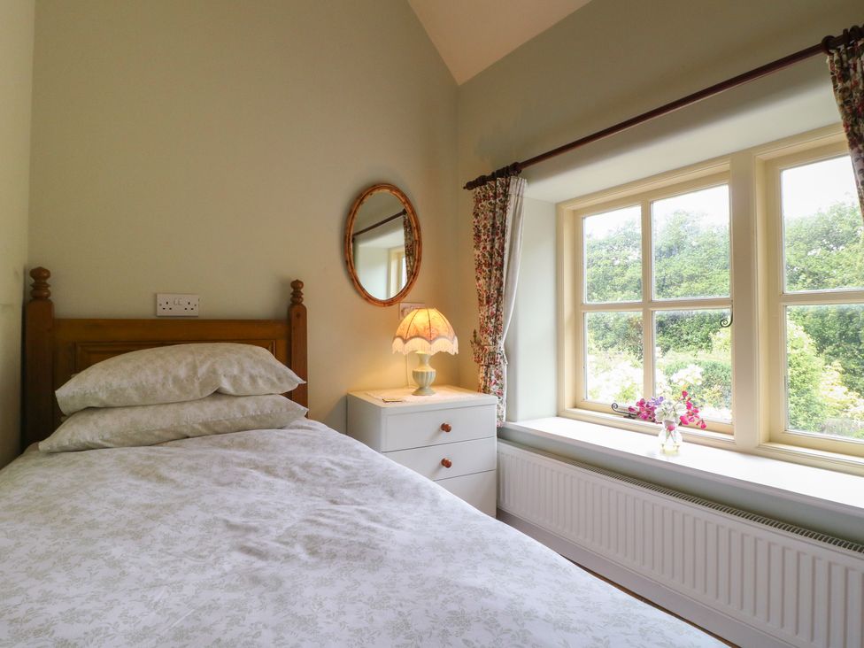 A bedroom with a bed and a mirror at Just A Cottage, Newlands Farm in Golden Valley near Riddings and Alfreton