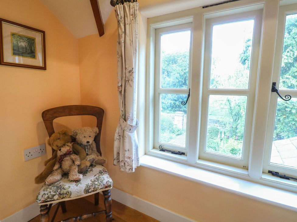 A chair with teddy bears by a window at Just A Cottage, Newlands Farm near Golden Valley near Riddings and Alfreton