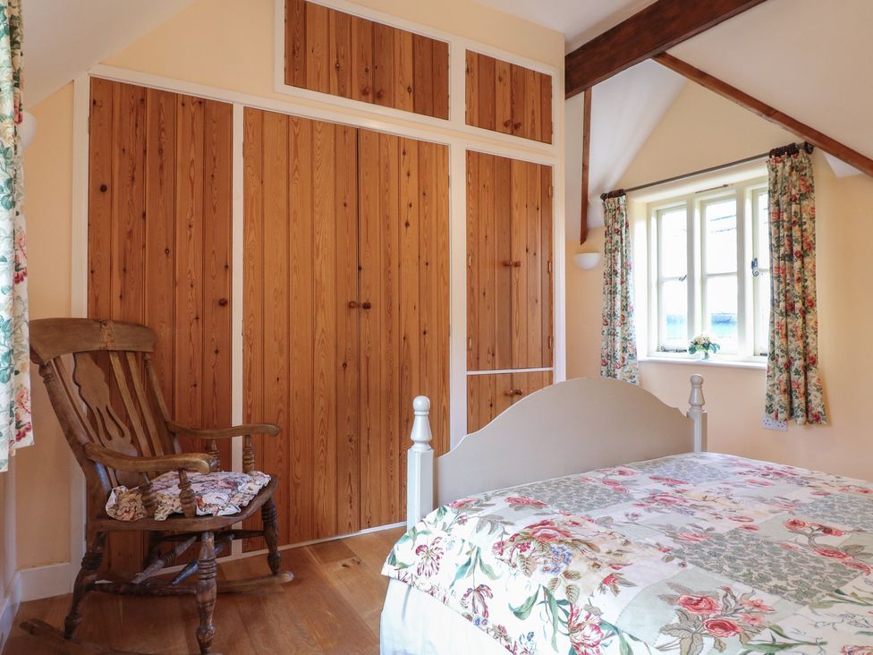 A bedroom with a bed and a rocking chair at Just A Cottage, Newlands Farm in Golden Valley near Riddings and Alfreton