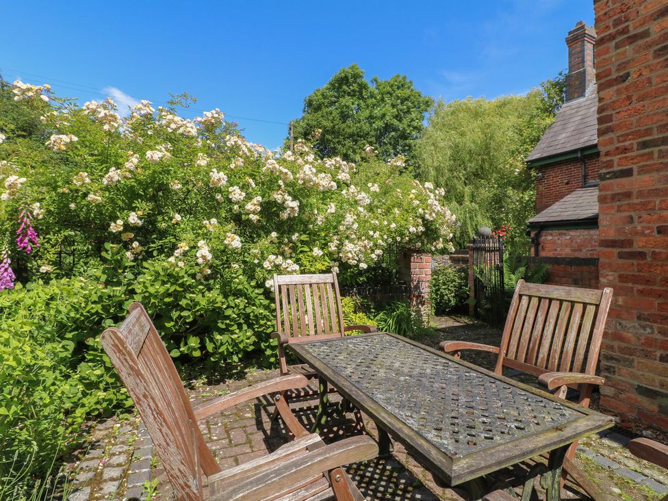 A garden with a table and chairs surrounded by flowers at Just A Cottage, Newlands Farm in Golden Valley near Riddings and Alfreton