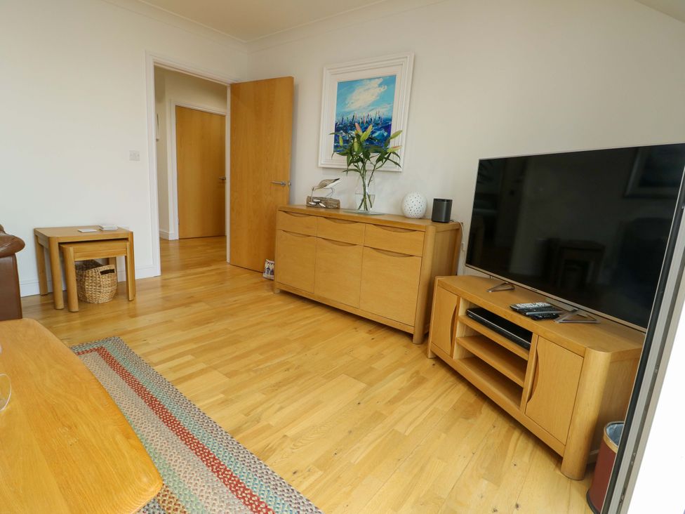 A living room with furniture and a television at Maelog, 14 Tides Reach in Rhosneigr