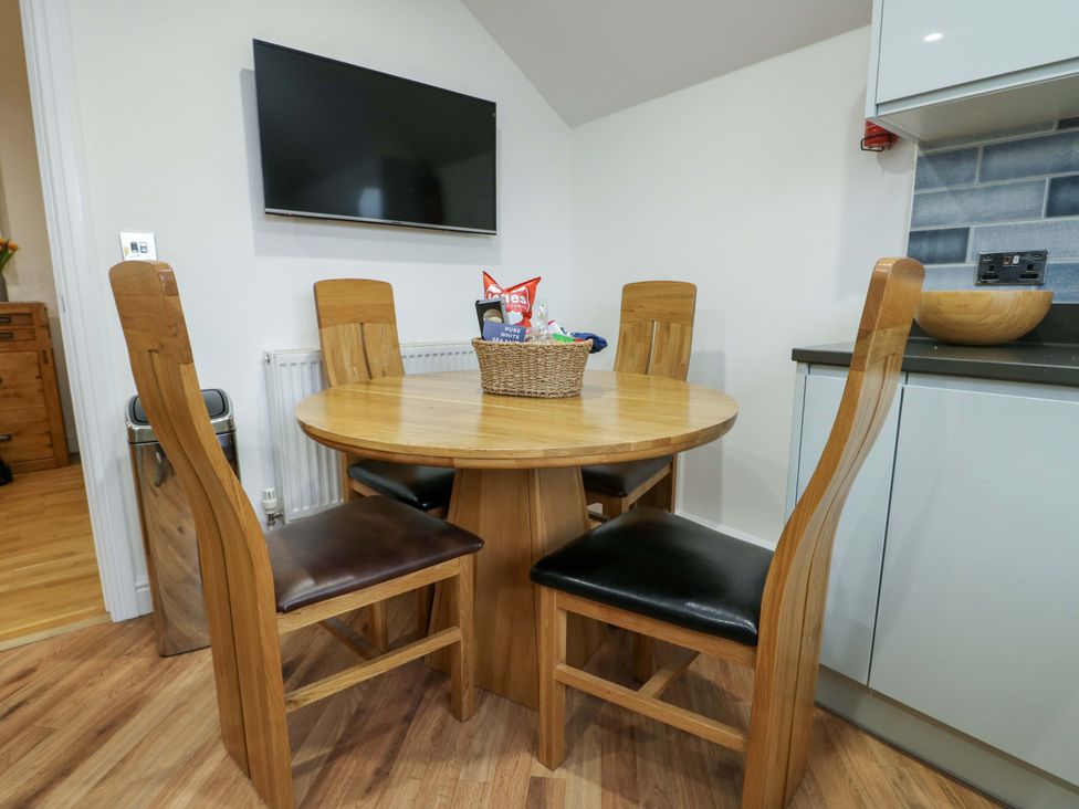 A dining room with a round wooden table and chairs at Maelog, 14 Tides Reach, Rhosneigr