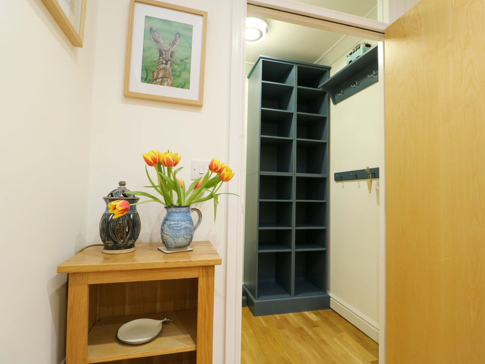 A hallway with a flower vase and framed artwork at Maelog, 14 Tides Reach Rhosneigr