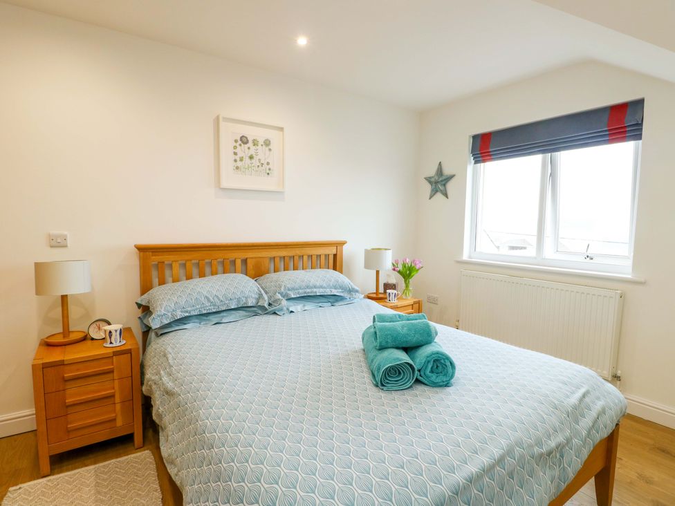 A bedroom with a bed and bedside table at Maelog, 14 Tides Reach Rhosneigr
