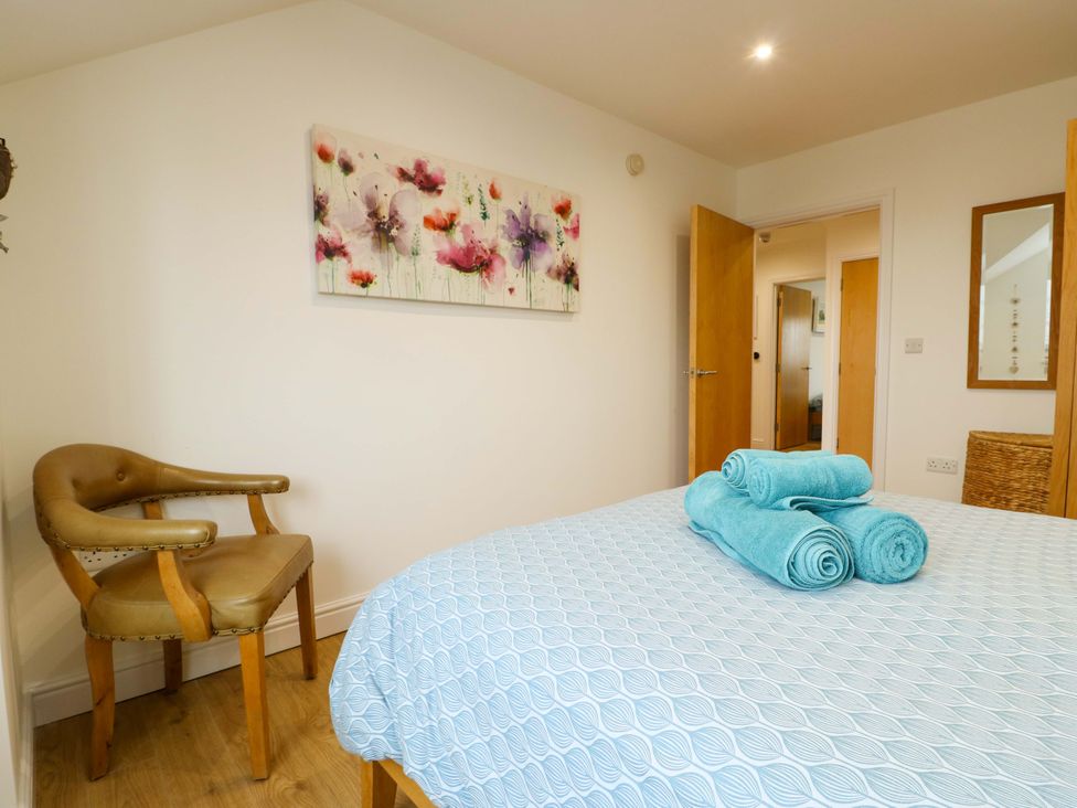 A bedroom with a bed and chair at Maelog, 14 Tides Reach Rhosneigr