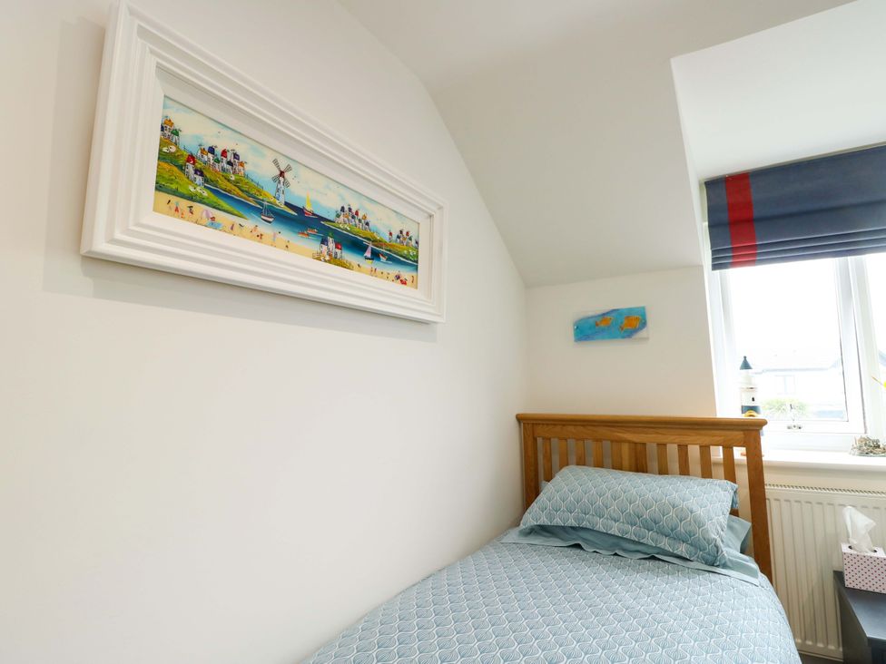 A bedroom with a bed and wall art at Maelog, 14 Tides Reach in Rhosneigr