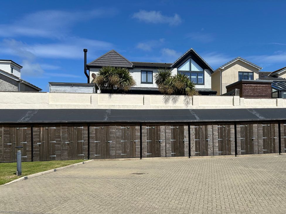 A row of garages and houses with a palm tree at Maelog, 14 Tides Reach, Rhosneigr
