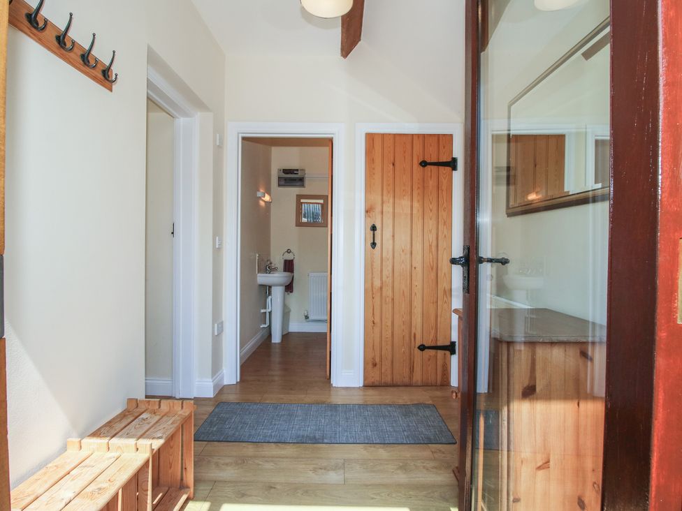 A hallway with a bench and coat hooks at The Wainhouse in Bockleton near Tenbury Wells