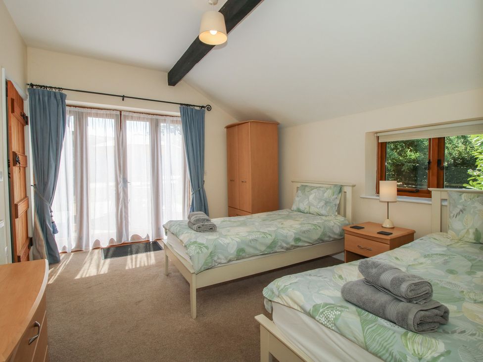 A bedroom with two beds and a wardrobe at The Wainhouse in Bockleton near Tenbury Wells