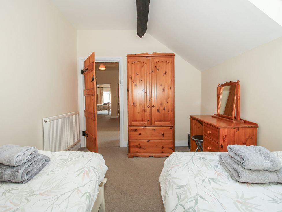 A bedroom with two beds and a wardrobe at The Wainhouse in Bockleton near Tenbury Wells