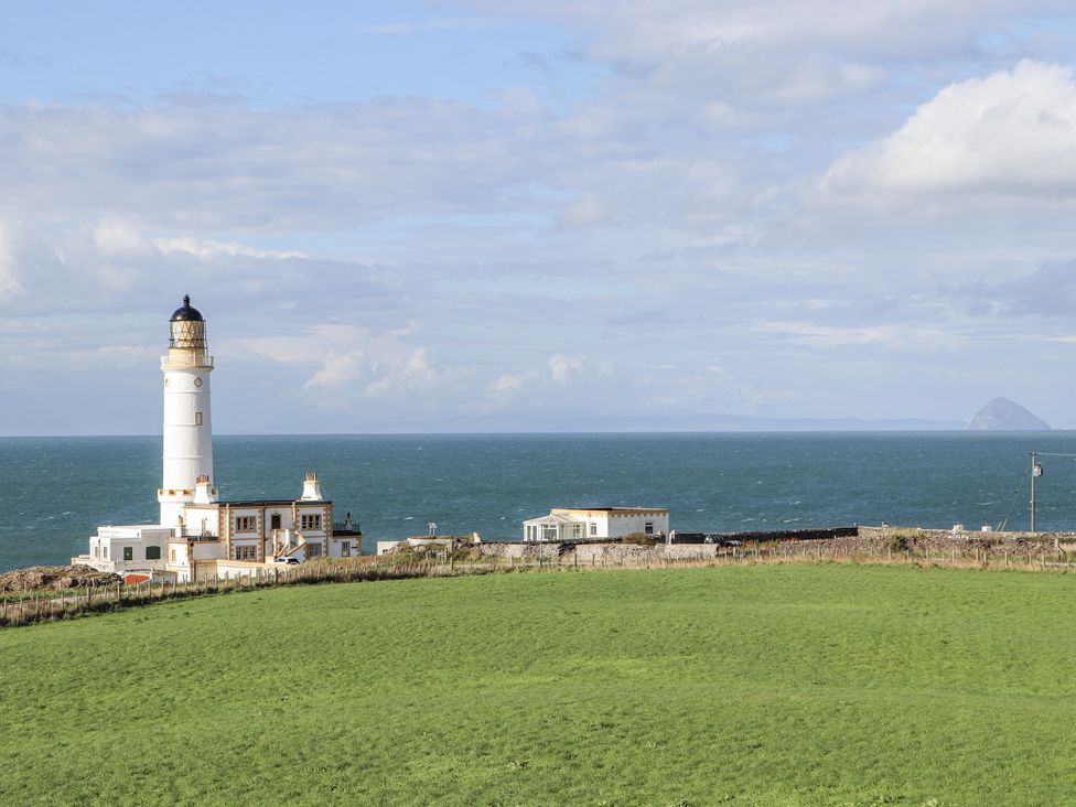 A lighthouse and building near the sea at Corsewall Castle Farm Lodges in Kirkcolm