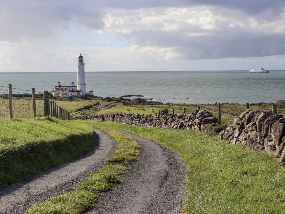 A lighthouse near the ocean with a road leading up at Corsewall Castle Farm Lodges in Kirkcolm